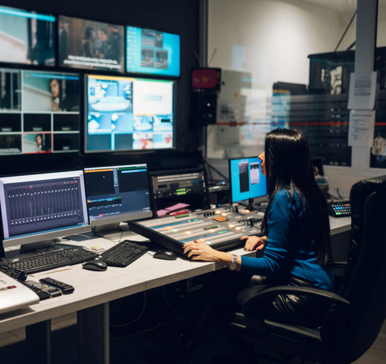 Journalist managing multiple screens in a fast-paced newsroom, illustrating high-volume editorial workflows and real-time content production